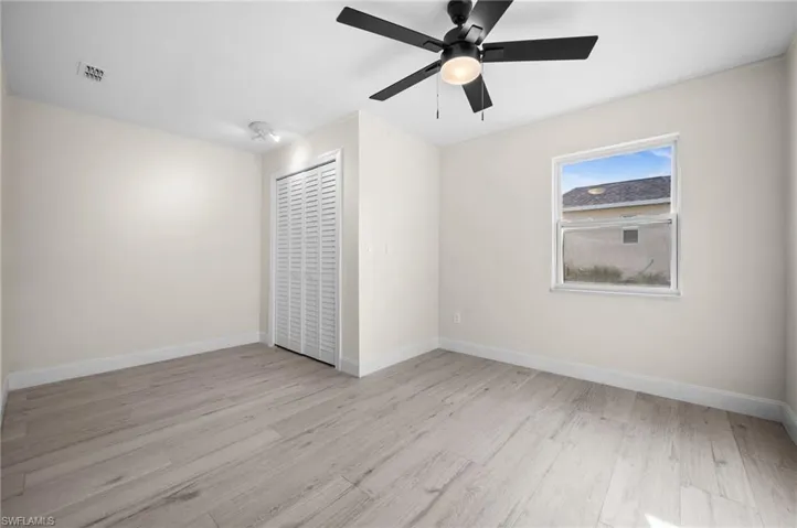 Unfurnished room featuring a ceiling fan, visible vents, baseboards, and wood finished floors