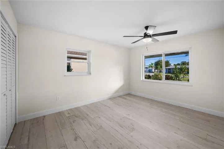 Unfurnished bedroom featuring light wood-style flooring, multiple windows, and baseboards