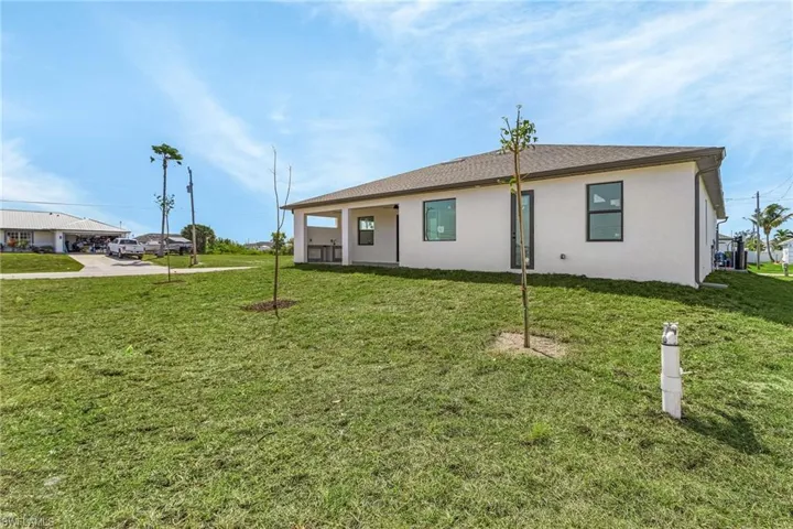 Back of property featuring stucco siding and a lawn