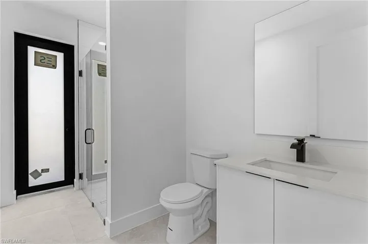 Full bathroom featuring tile patterned flooring, vanity, toilet, baseboards, and a shower stall
