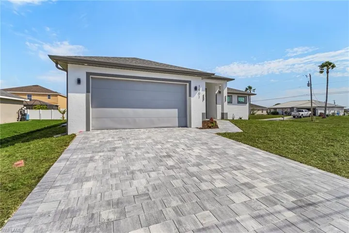 Single story home with stucco siding, a front lawn, and decorative driveway
