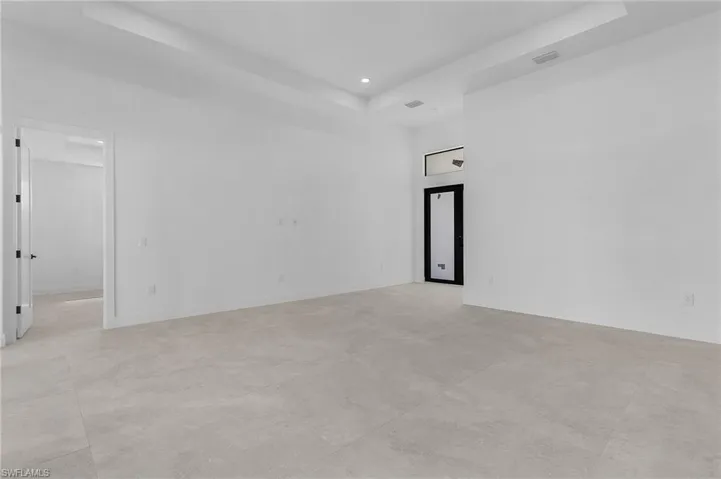 Spare room with a tray ceiling, recessed lighting, baseboards, a high ceiling, and visible vents