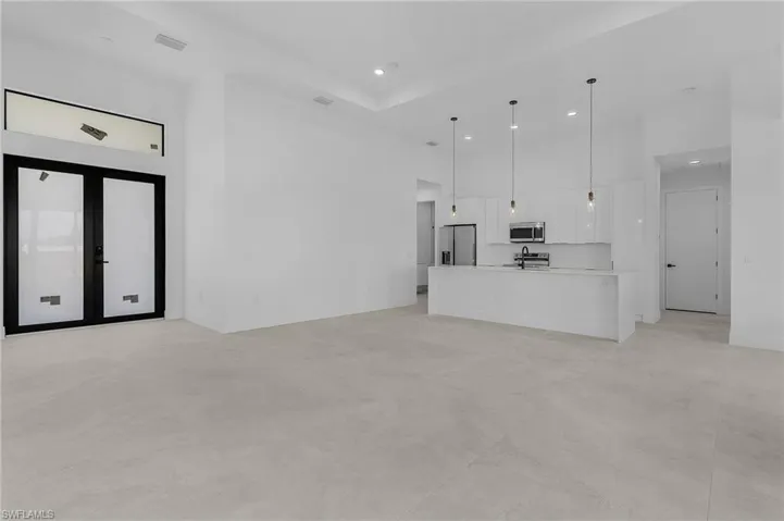Unfurnished living room with concrete flooring, visible vents, a high ceiling, and recessed lighting