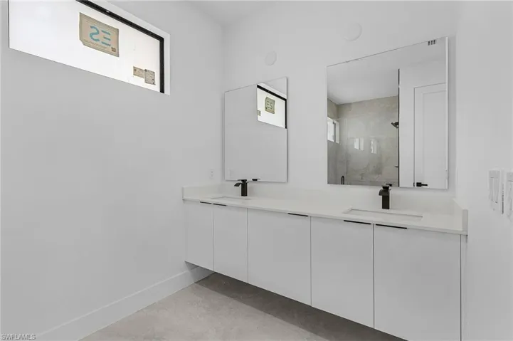 Full bathroom with baseboards, double vanity, a sink, and a shower stall