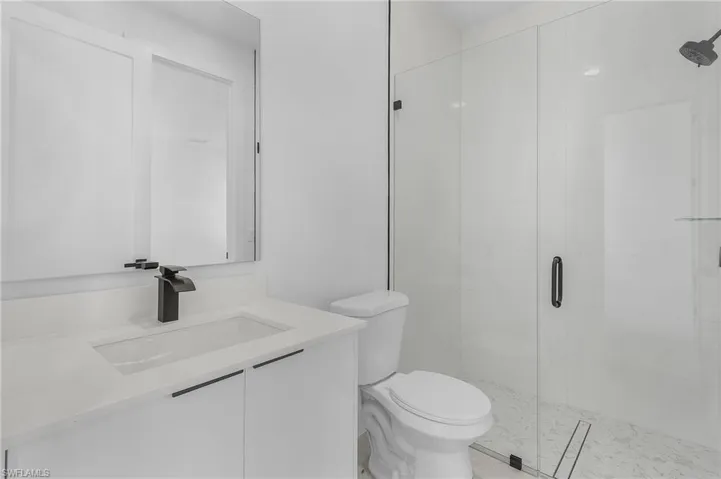 Bathroom featuring toilet, vanity, and a shower stall