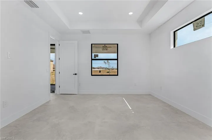 Spare room with a raised ceiling, recessed lighting, baseboards, and visible vents