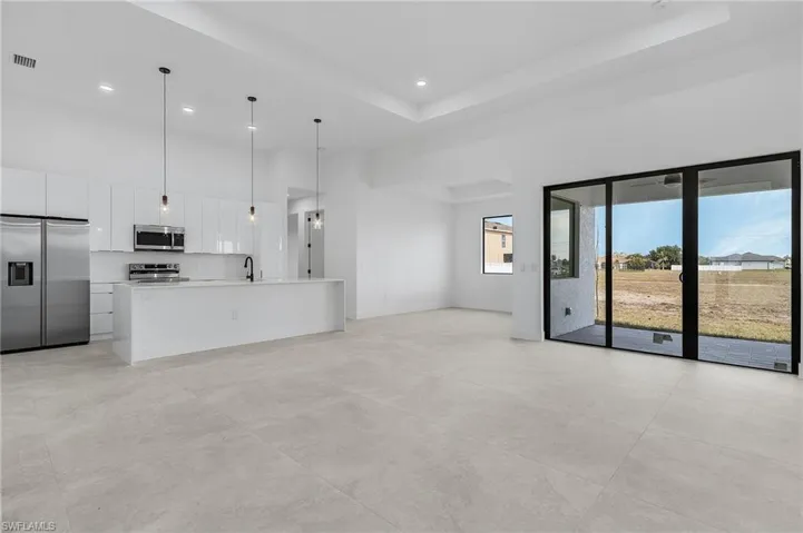 Unfurnished living room featuring a sink, baseboards, visible vents, a towering ceiling, and recessed lighting