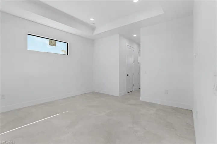Unfurnished room featuring baseboards, a tray ceiling, recessed lighting, and concrete flooring