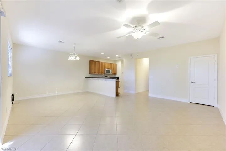 Unfurnished living room with recessed lighting, a ceiling fan, a chandelier, and light tile patterned flooring