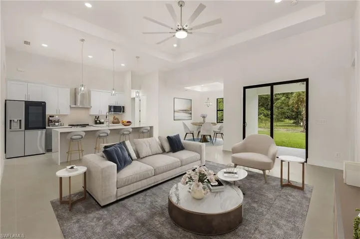 Living room with ceiling fan, a tray ceiling, and light tile patterned floors