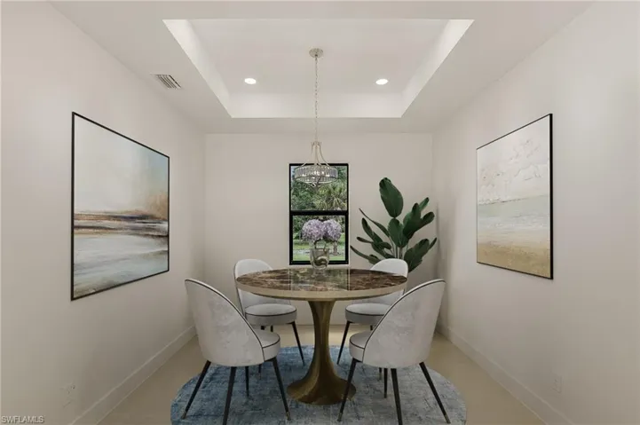 Dining space with tile patterned floors, a chandelier, and a tray ceiling