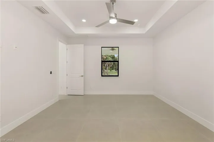 Tiled spare room with a raised ceiling and ceiling fan