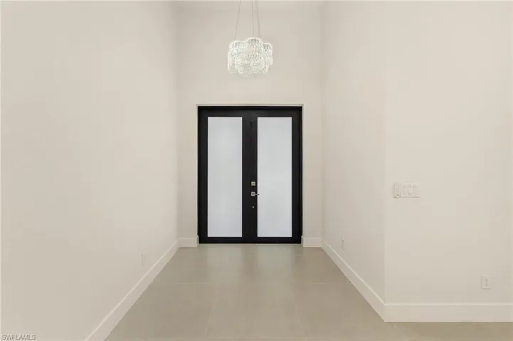Foyer featuring light tile patterned flooring and an inviting chandelier