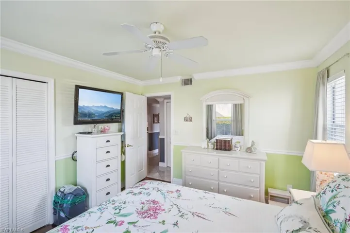 Bedroom with a closet, ceiling fan, and ornamental molding