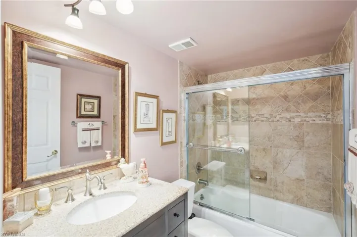 Full bathroom featuring combined bath / shower with glass door, vanity, and toilet