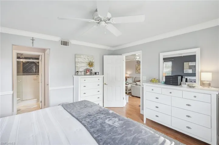 Bedroom with ensuite bathroom, light hardwood / wood-style floors, and crown molding