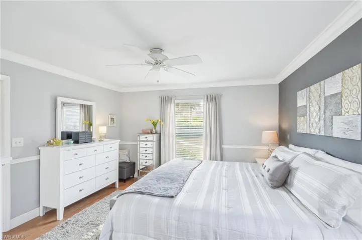 Bedroom featuring ceiling fan, light hardwood / wood-style floors, and crown molding