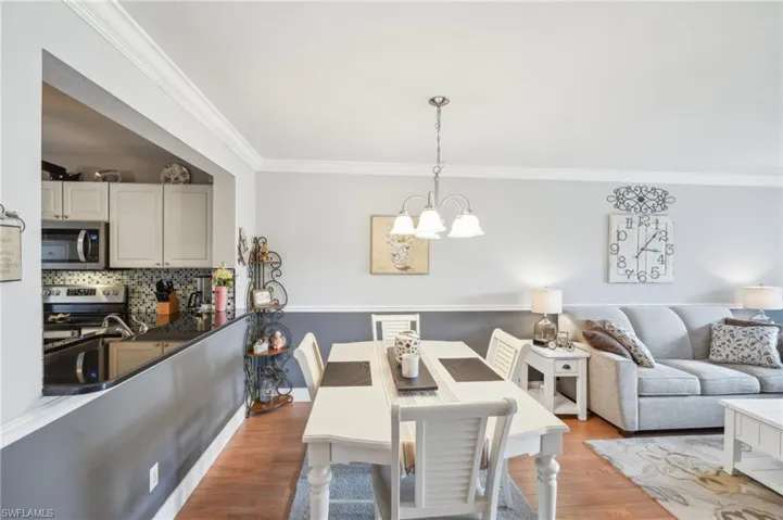 Dining space featuring light hardwood / wood-style floors, an inviting chandelier, crown molding, and sink