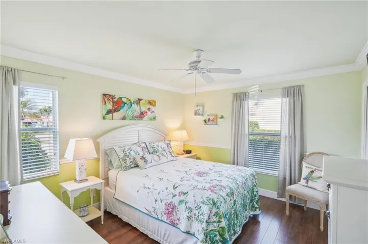 Bedroom featuring multiple windows, dark hardwood / wood-style flooring, ornamental molding, and ceiling fan