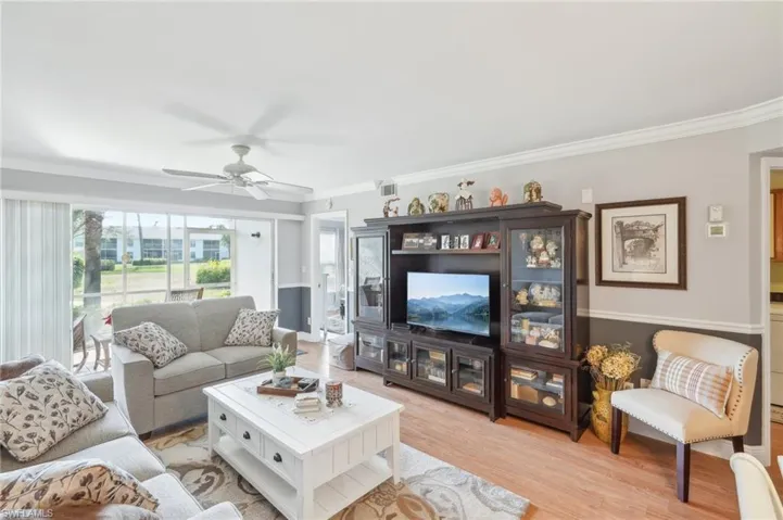 Living room featuring light hardwood / wood-style floors, crown molding, and ceiling fan