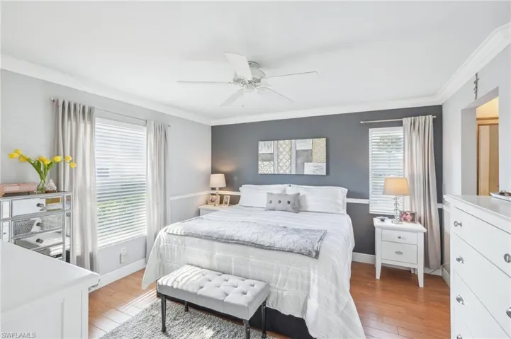 Bedroom featuring ceiling fan, light wood-type flooring, and crown molding