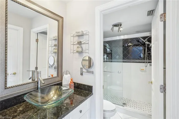 Bathroom featuring toilet, vanity, and an enclosed shower