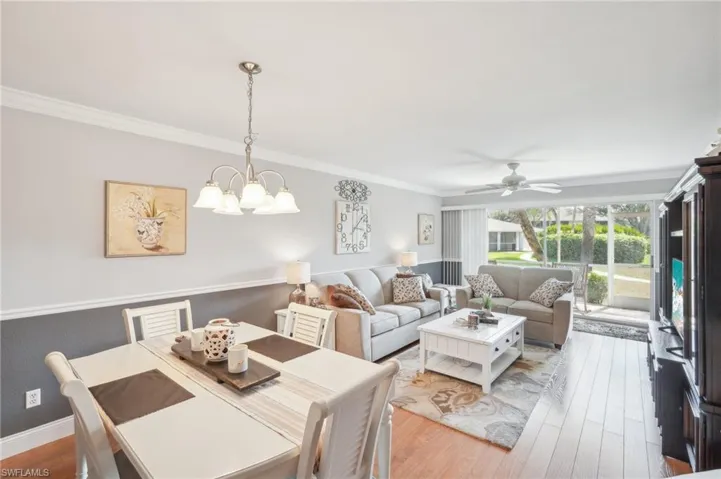 Living room featuring hardwood / wood-style floors, crown molding, and ceiling fan with notable chandelier