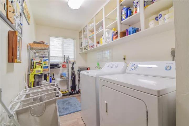 Clothes washing area with independent washer and dryer and light hardwood / wood-style flooring