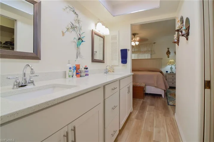 Bathroom with hardwood / wood-style flooring, ceiling fan, and dual bowl vanity