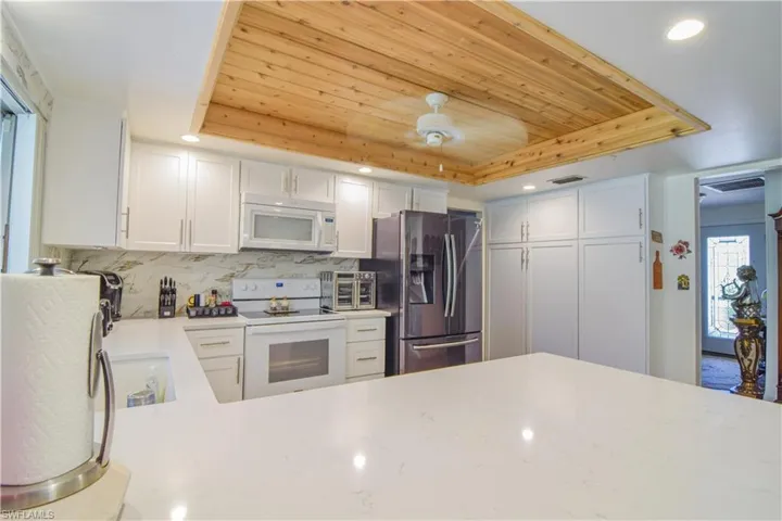 Kitchen featuring white appliances, plenty of natural light, and a tray ceiling