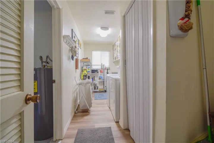 Hall with washing machine and dryer, electric water heater, and light wood-type flooring