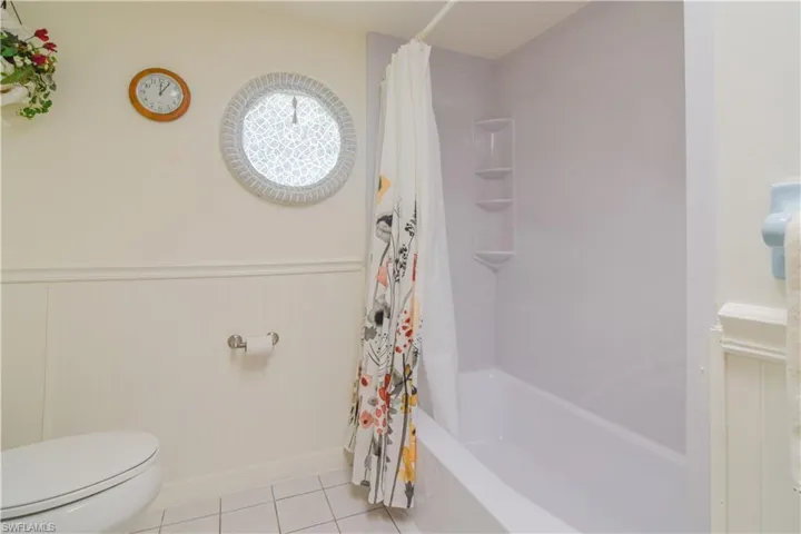 Bathroom featuring tile flooring, toilet, and shower / tub combo with curtain