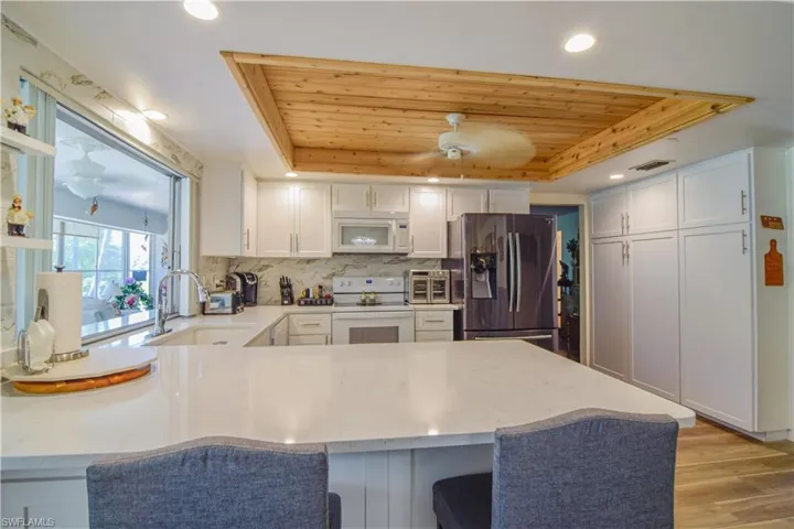 Kitchen featuring white appliances, wood ceiling, light wood-type flooring, and a raised ceiling