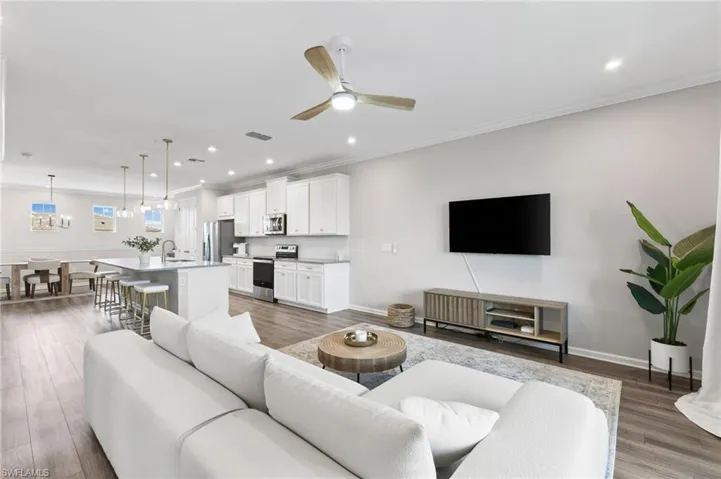 Living room featuring light wood-style flooring, a ceiling fan, recessed lighting, and crown molding