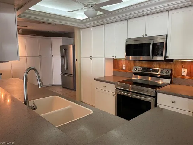 Kitchen with stainless steel appliances, white cabinets, and a ceiling fan