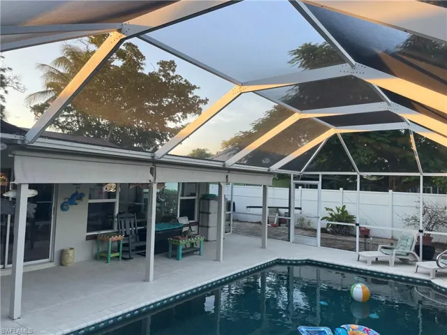 View of pool with glass enclosure, a patio, and a sunroom