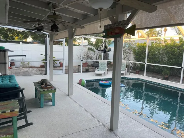 View of swimming pool featuring ceiling fan and a lanai