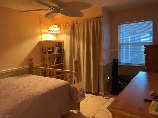 Bedroom with light tile patterned floors, a textured ceiling, and a ceiling fan