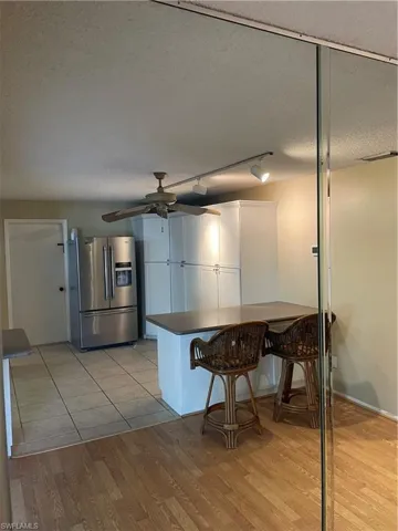 Kitchen featuring dark countertops, fridge, a kitchen breakfast bar, a textured ceiling, and light wood-style flooring