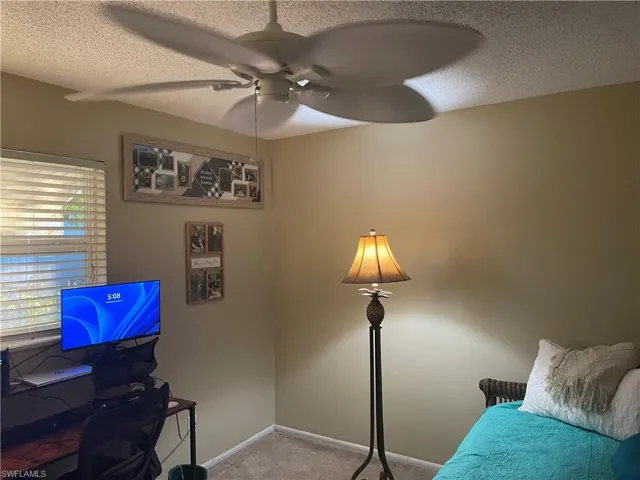 Office space featuring a textured ceiling, light colored carpet, and ceiling fan