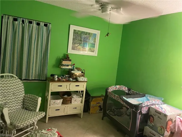 Tiled bedroom with a textured ceiling and ceiling fan
