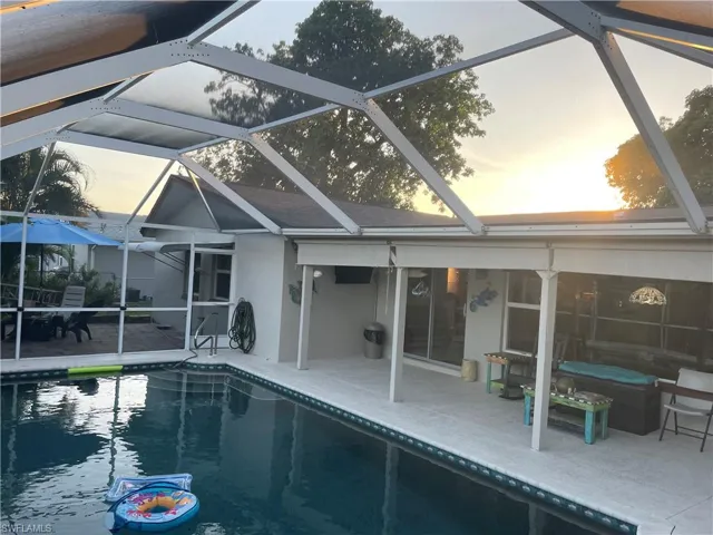 Pool at dusk featuring an outdoor pool, a lanai, and a sunroom