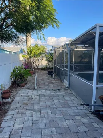 Fenced backyard with glass enclosure, a patio, and a sunroom