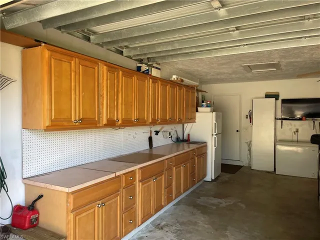 Kitchen with brown cabinets, freestanding refrigerator, and concrete floors