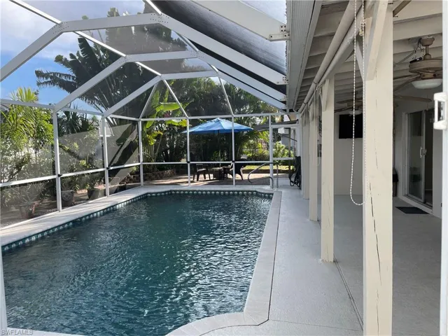Swimming pool featuring a patio, a sunroom, and glass enclosure