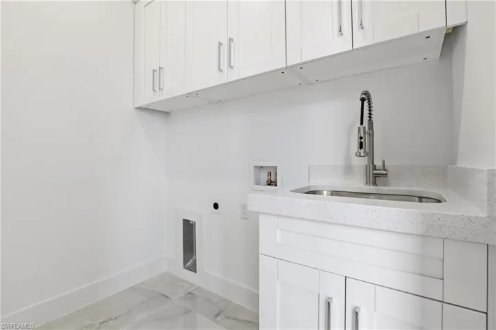 Laundry room with light marble finish flooring, hookup for an electric dryer, cabinet space, and hookup for a washing machine