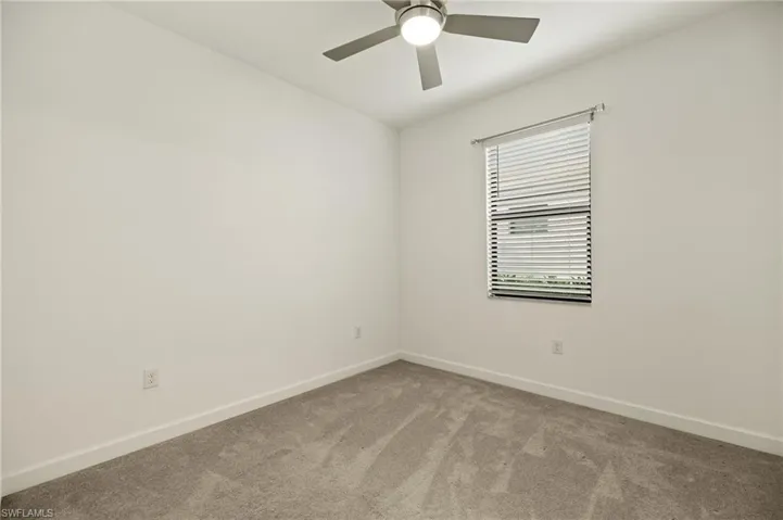 Carpeted spare room featuring ceiling fan