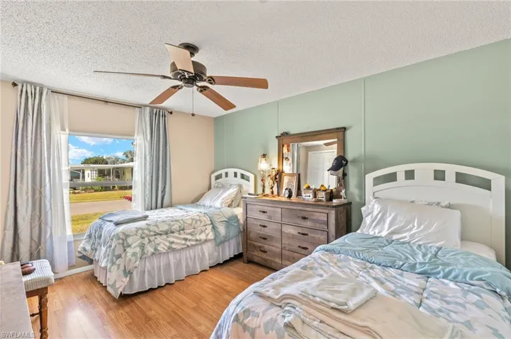 Bedroom featuring ceiling fan, hardwood / wood-style flooring, and a textured ceiling