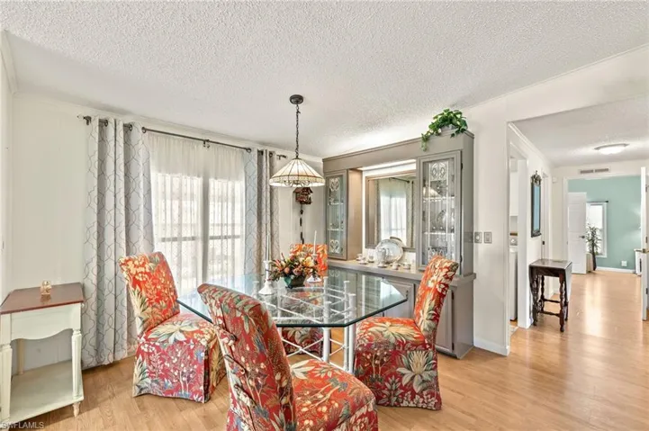 Dining space with ornamental molding, light hardwood / wood-style flooring, and a textured ceiling