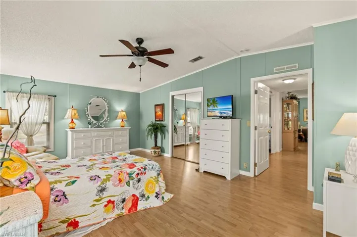 Bedroom with wood-type flooring, lofted ceiling, ornamental molding, ceiling fan, and a textured ceiling